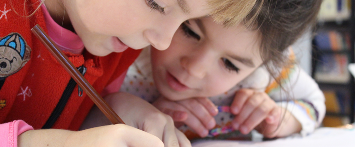 Nursery school children writing in a book