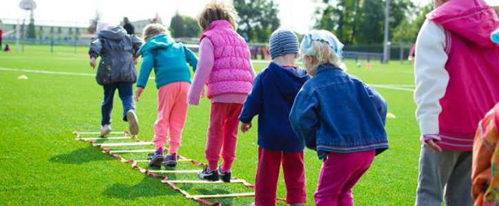 Plant ysgol Derbyn yn chwarae ar y glaswellt